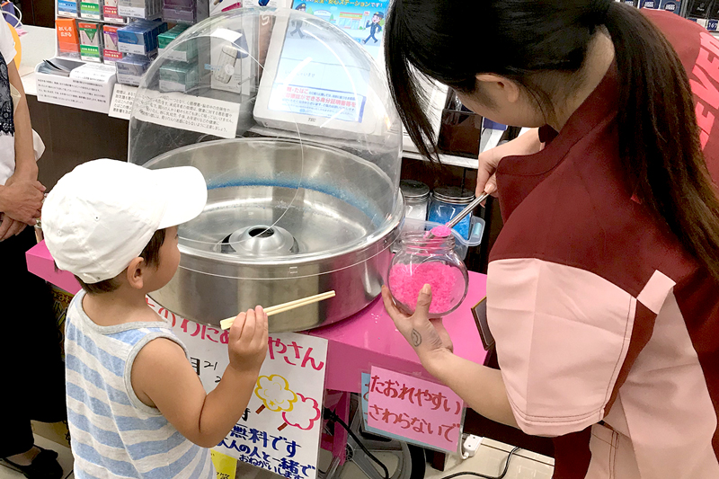 ご来店のお子様に綿菓子をつくるスタッフ